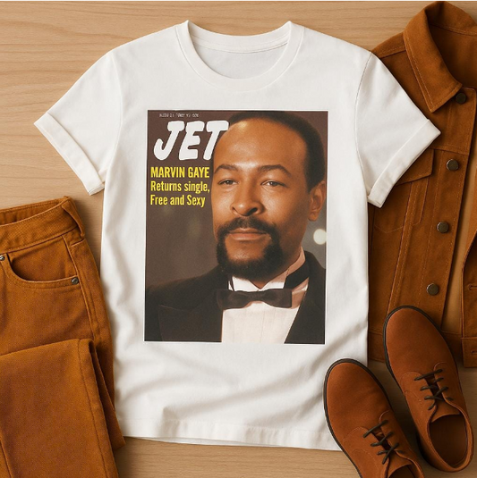 
White unisex t-shirt featuring a reproduction of a JET Magazine cover with Marvin Gaye in a black tuxedo and bow tie. The cover shows "Marvin Gaye Returns Single, Free and Sexy" headline. Shirt is styled with tan corduroy jacket, jeans, and brown leather shoes on a wooden background.