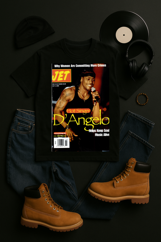 Black unisex t-shirt featuring a reproduction of the July 3, 2000 JET Magazine cover with D'Angelo performing shirtless with a microphone. The cover shows "Hot Singer D'Angelo - Helps Keep Soul Music Alive" headline in yellow text. Shirt is styled with black jeans, tan Timberland boots, vinyl records, headphones, and a beanie on a dark background.